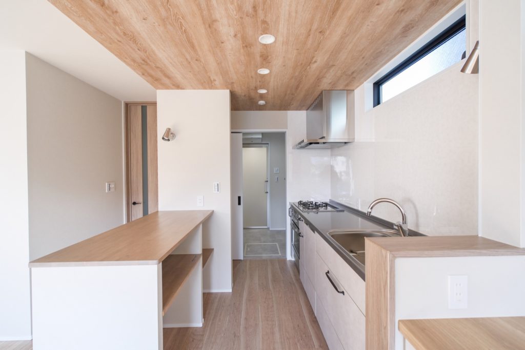 木目調の天井とフローリングが統一感を醸し出す、明るくモダンなカウンターキッチンの施工事例。